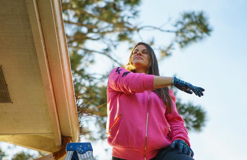 Lady cleaning out roof gutter
